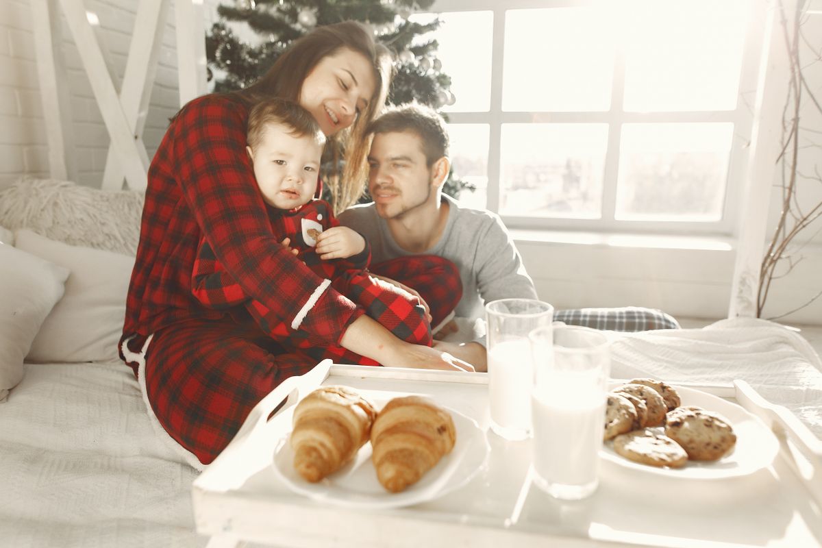 A cheerful family enjoying a holiday breakfast in cozy pajamas, complete with croissants and milk.