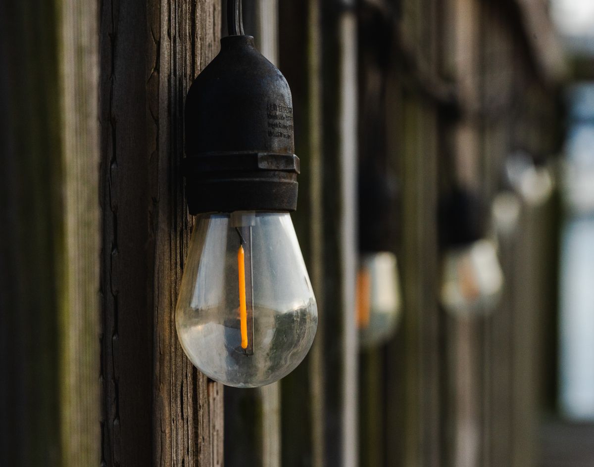 Vintage outdoor light bulbs hanging on a wooden structure create a rustic atmosphere.