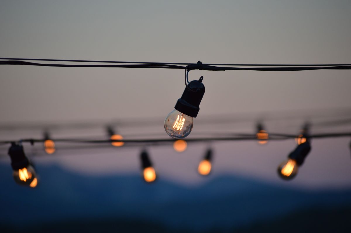 Illuminated string lights against the twilight sky create a warm ambiance outdoors.