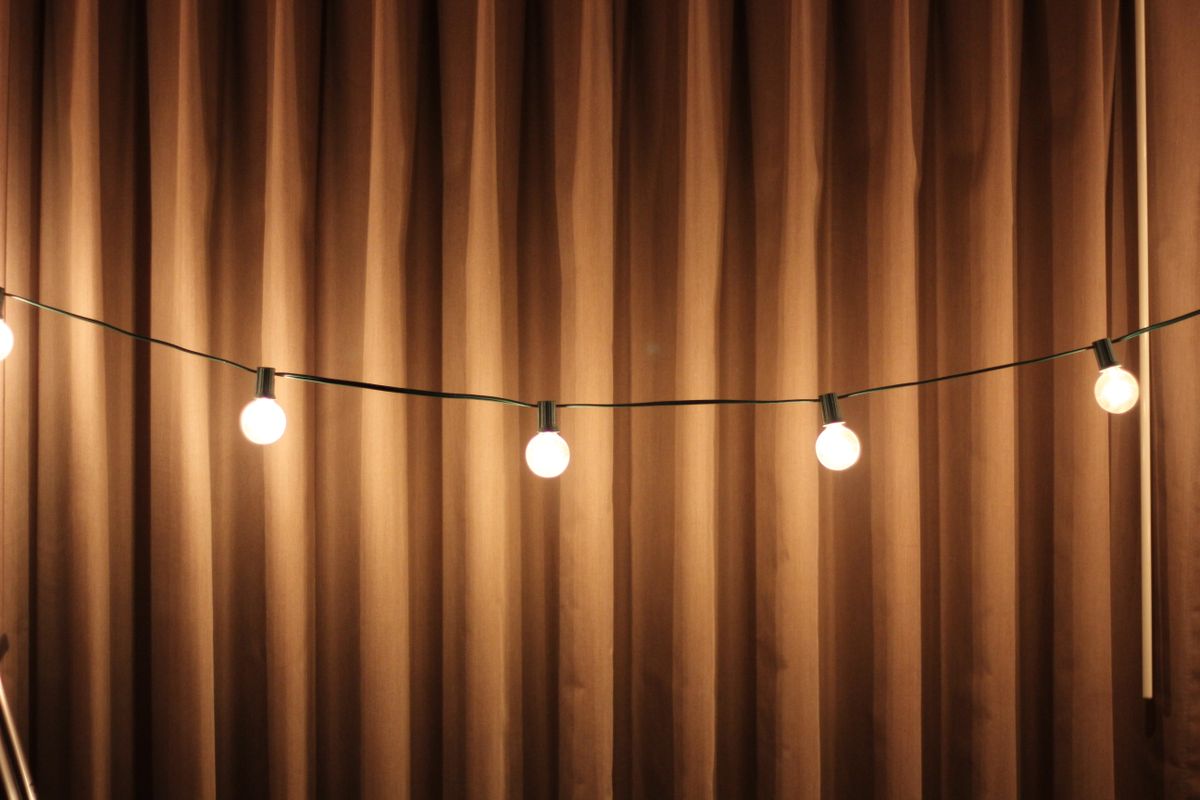 Cozy warm string lights illuminating a brown draped curtain for soft ambient lighting.