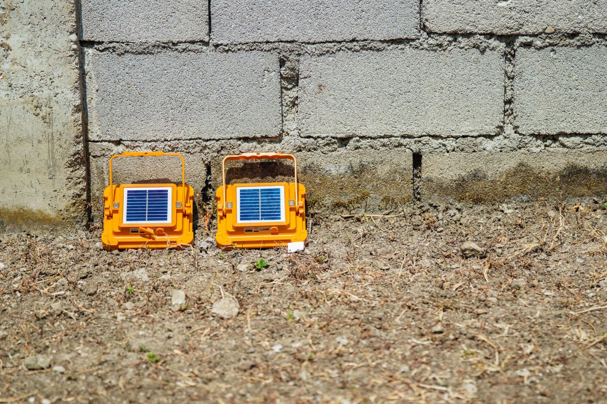 Bright orange portable solar lights sit against a concrete wall, capturing sunlight outdoors.
