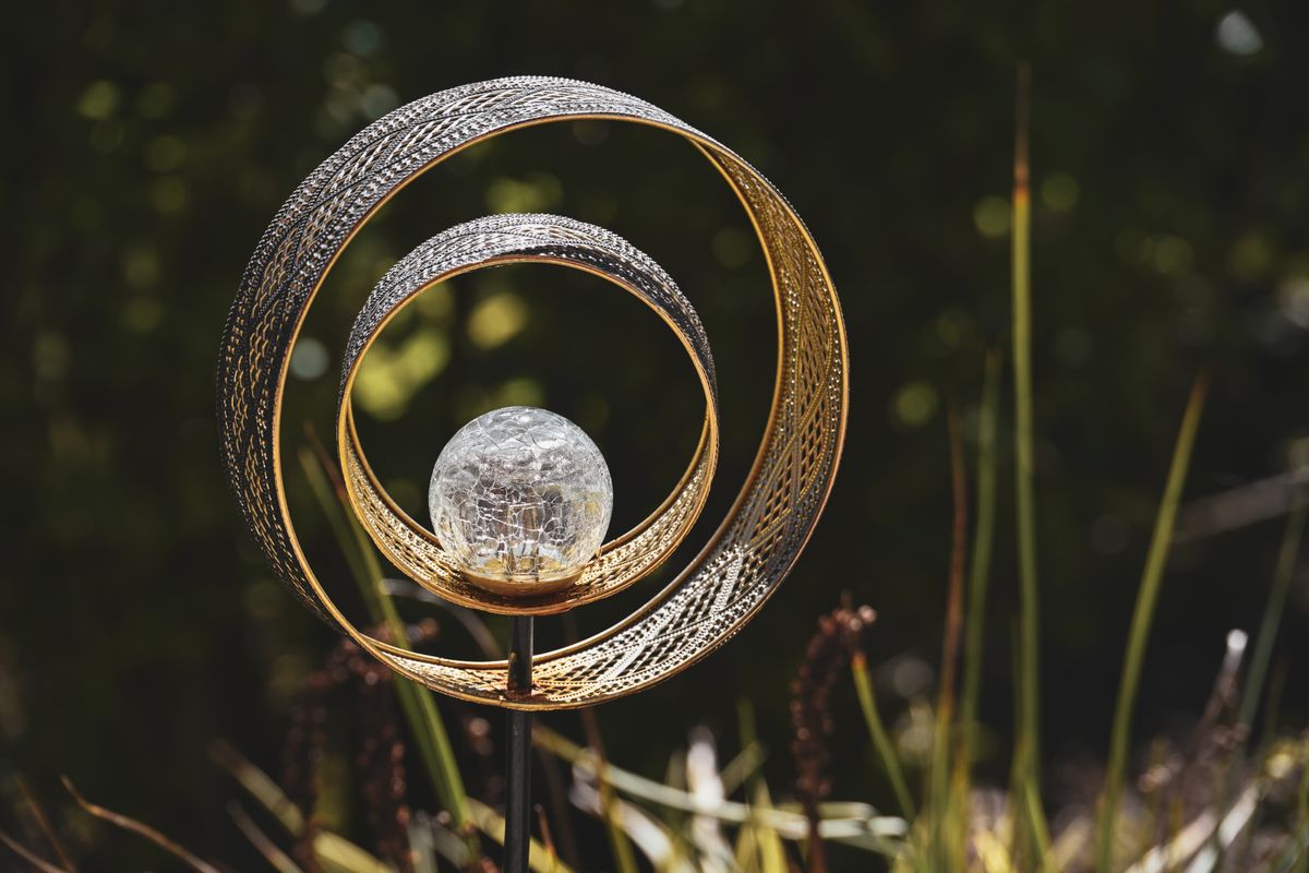 An artistic metal garden sculpture with a decorative glass orb, perfect for outdoor decor.
