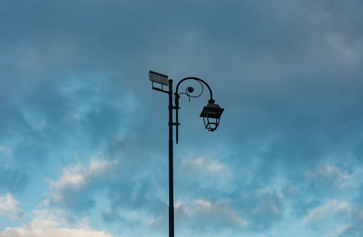 A street lamp with a solar panel set against a dramatic cloudy sky in Montesarchio, Italy.