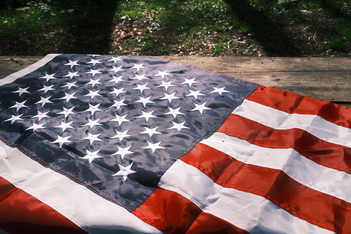 Photo of American flag on wooden surface in outdoor setting with natural lighting and shadows.