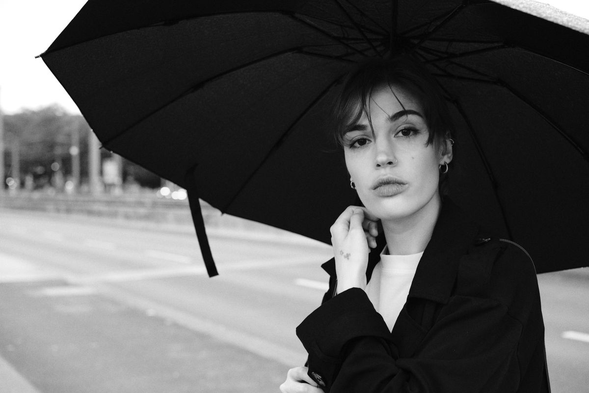 Black and white portrait of a woman with an umbrella on a rainy day in Cologne.