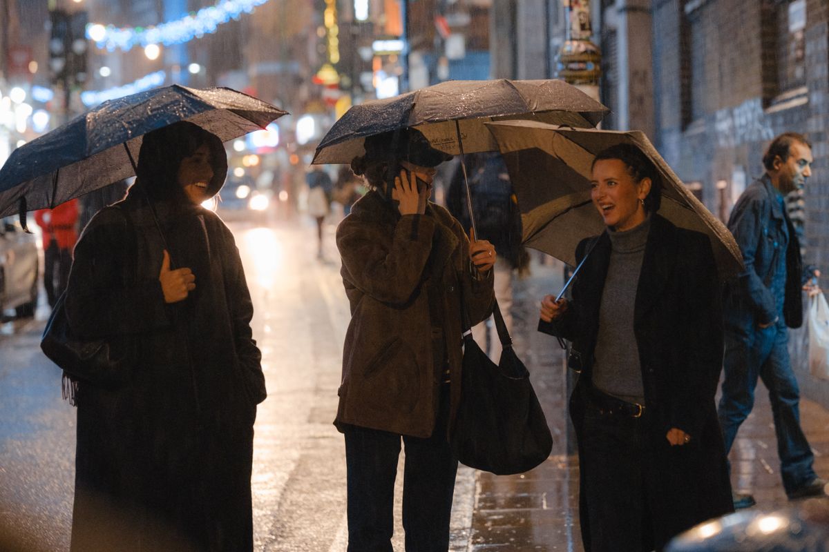 Three women under umbrellas enjoying a rainy night city stroll.