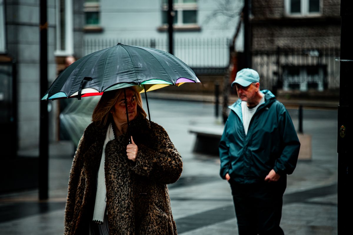 Candid urban scene of people in Ireland with umbrellas during rainy weather in a city setting.