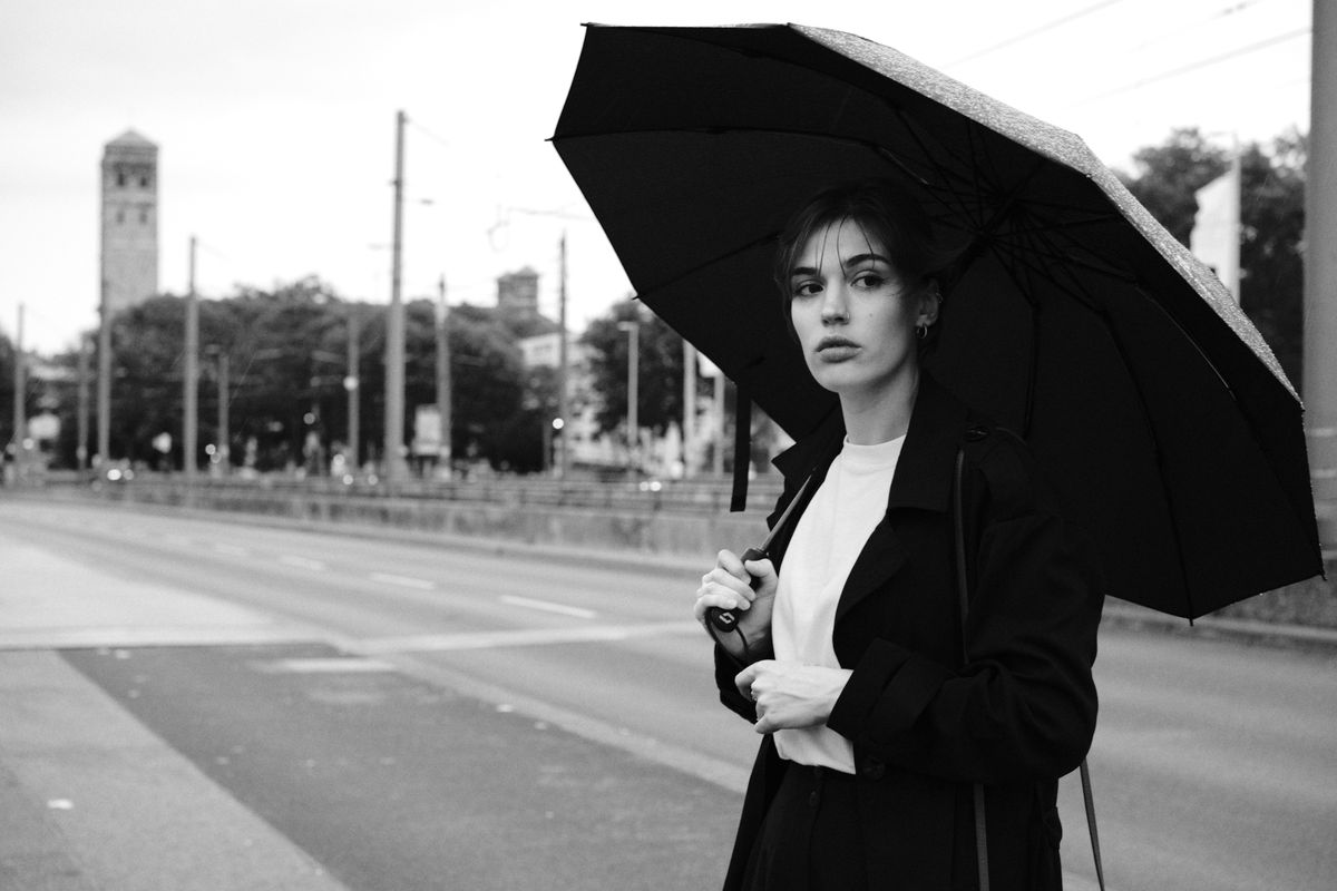 Elegant woman holding an umbrella on a rainy day in Cologne, Germany.