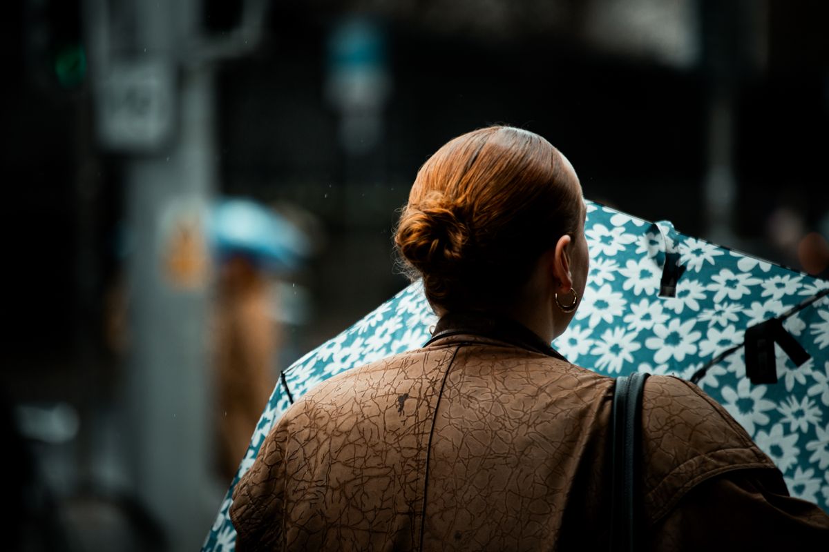 Woman holding floral umbrella in rainy Dublin street, creating a moody urban scene.