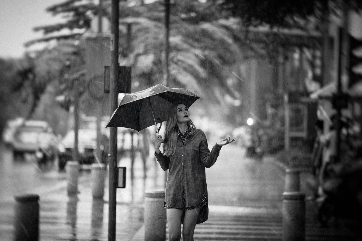 Woman enjoying a rainy day on a city street, holding an umbrella.
