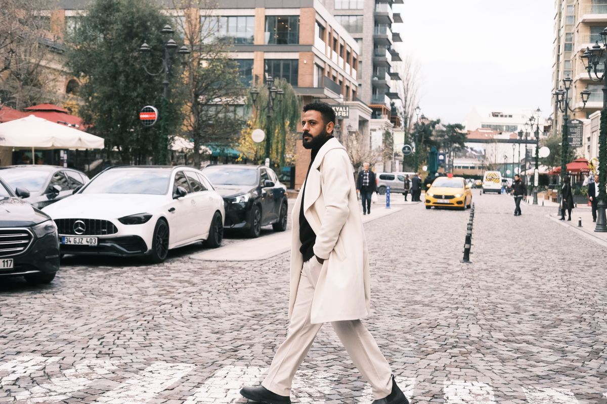 Stylish man in trench coat walking across a busy İstanbul street.