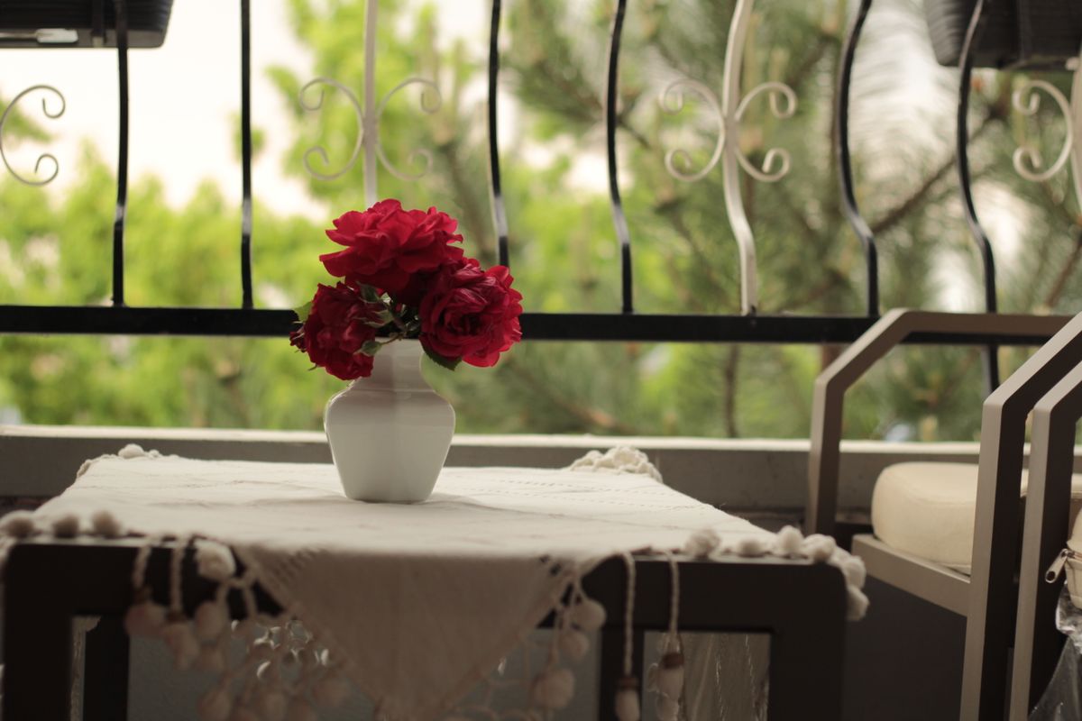 A charming balcony scene in Ankara with red roses in a vase on a table, perfect for a relaxing ambiance.