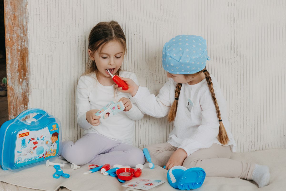 Two children playing dentist at home with a toy set, learning and having fun.