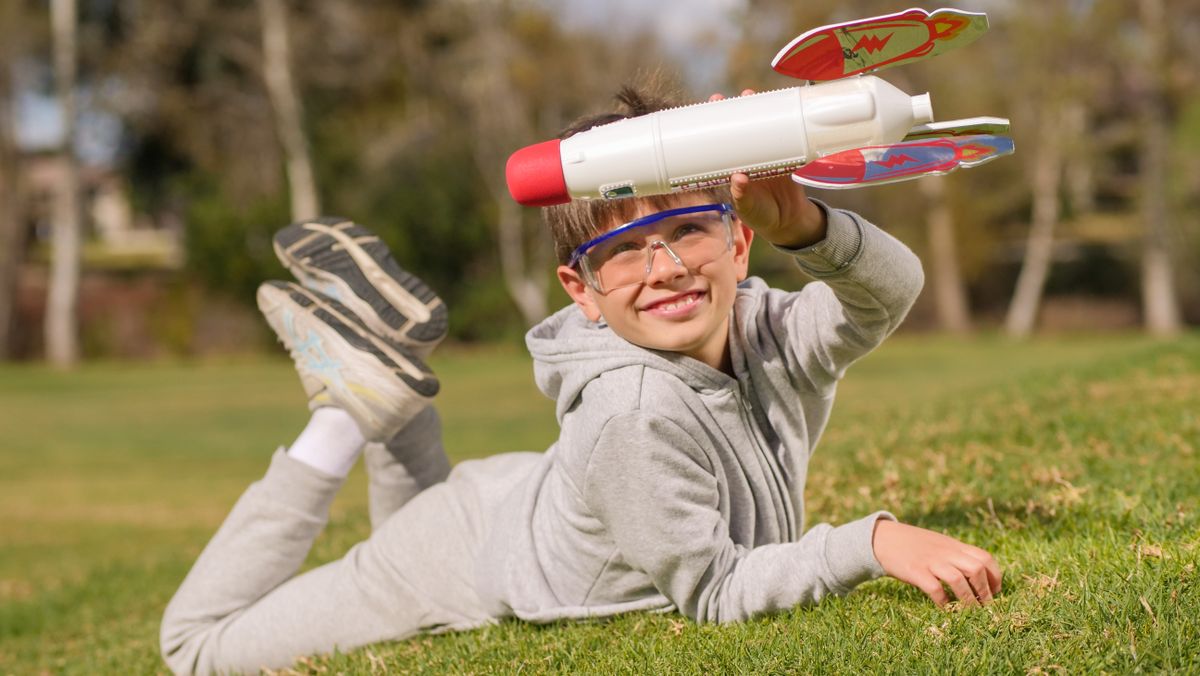 A joyful boy playing with a toy rocket in a sunny park, embracing imagination.