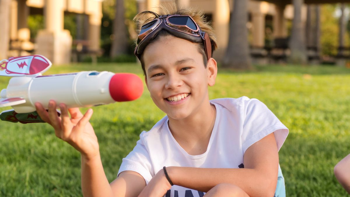 Joyful child playing with a toy rocket on a sunny day in the park.