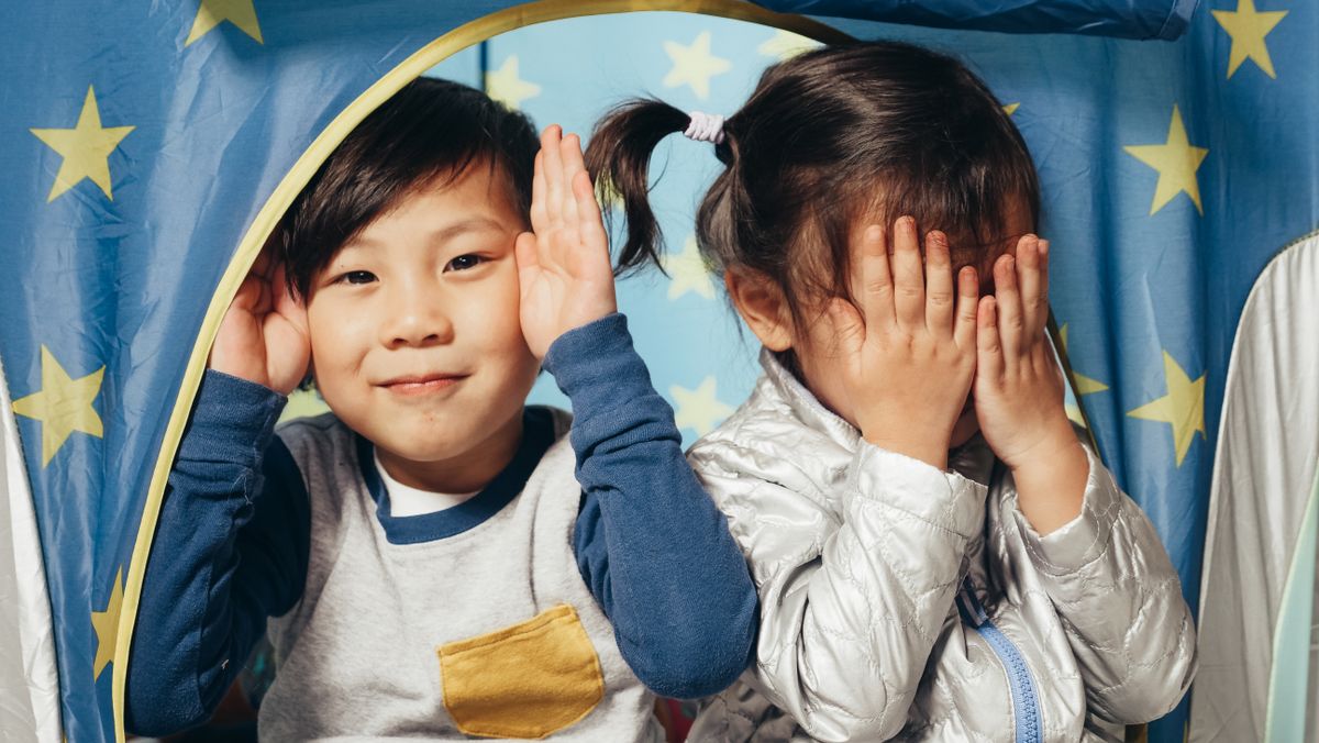 Two children playing joyfully under a starry tent indoors, having fun together.