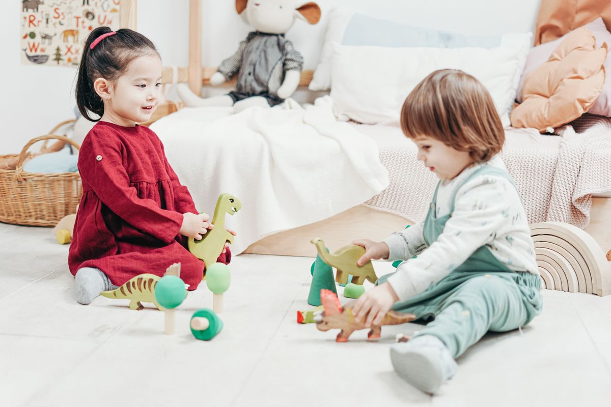Two kids playing with wooden toys in a cozy playroom setting, indoors.
