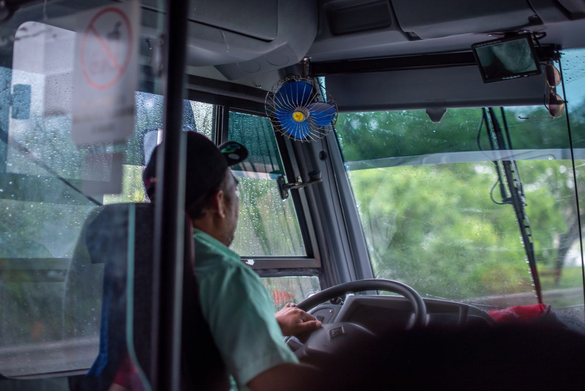 Bus driver navigating through rainy weather, view from the interior with visible windshield and raindrops.