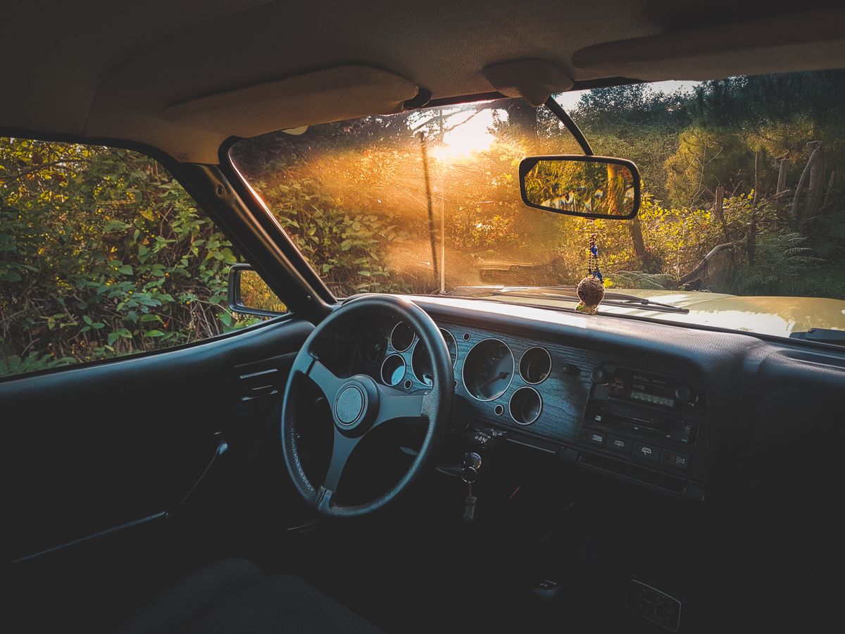 Interior view of a classic car with sunlight streaming through the windshield creating a warm ambiance.