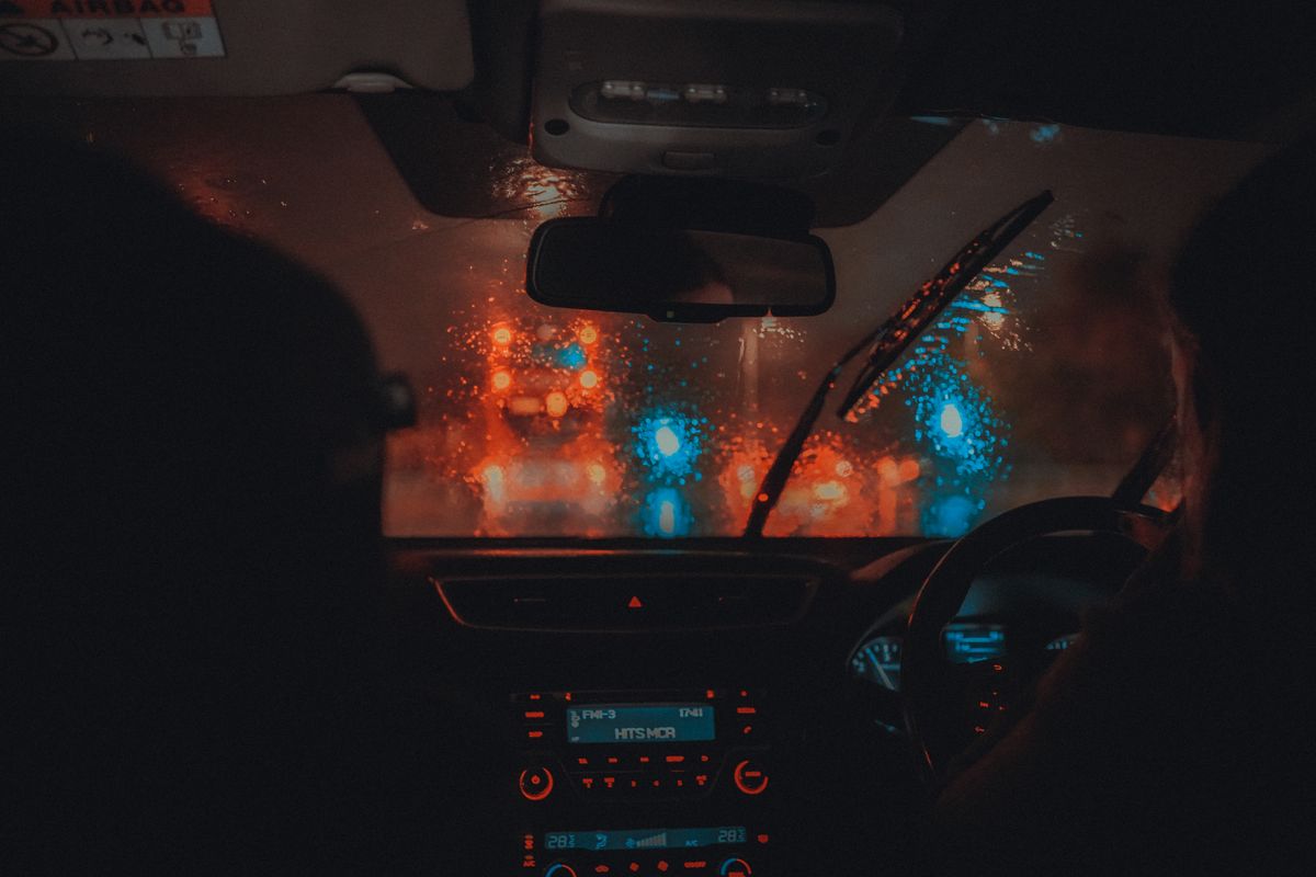 Cinematic view from a car interior driving through Manchester at night in the rain.