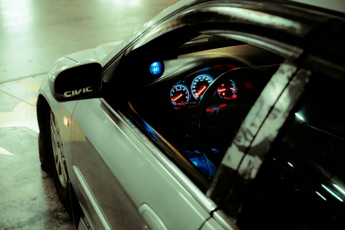 Interior view of a car showing a dashboard with illuminated gauges in a parking garage.