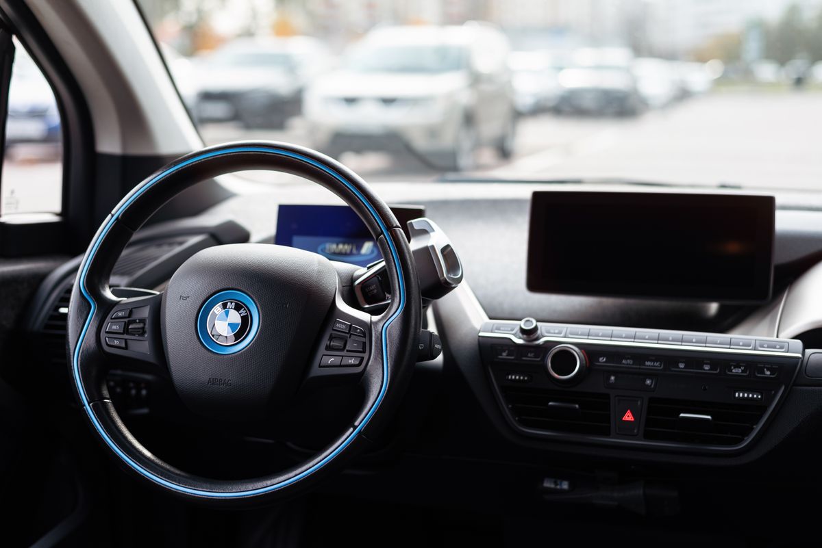 Interior of a modern car showcasing sleek dashboard and steering wheel in an urban setting.