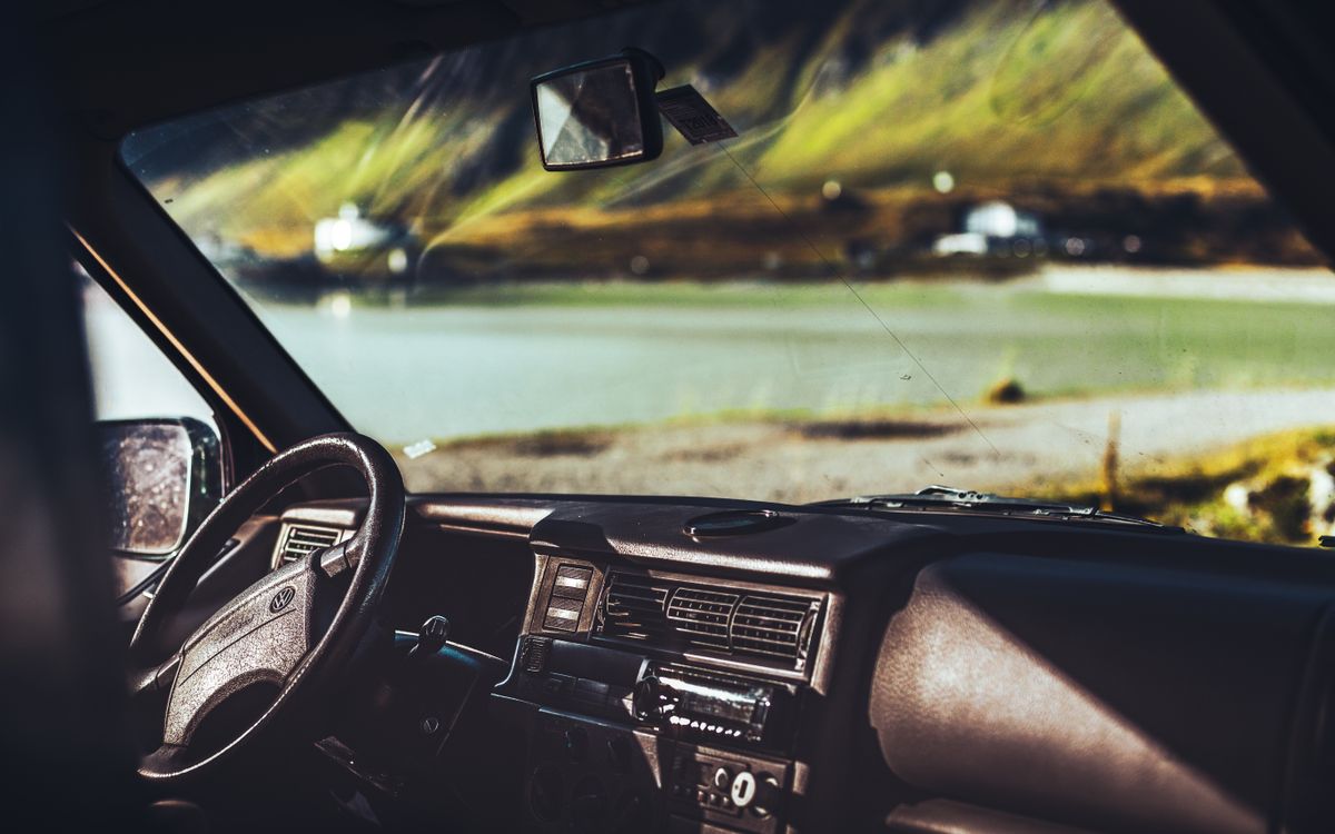 Inside a car overlooking a scenic lake in Austria, showcasing the dashboard and steering wheel.