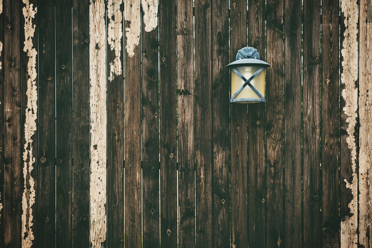 A weathered wooden fence with a vintage lantern adding rustic charm.