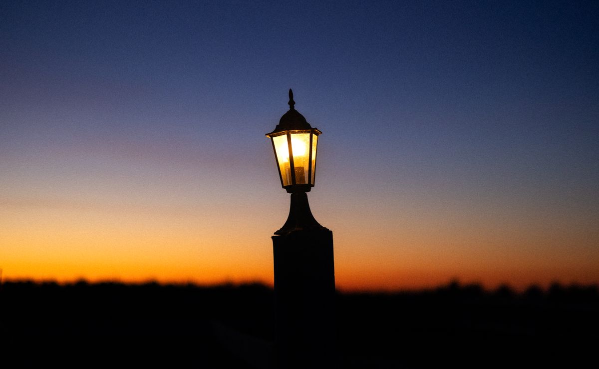 A serene sunset with a silhouette of a lamp post against a colorful evening sky in Poland.