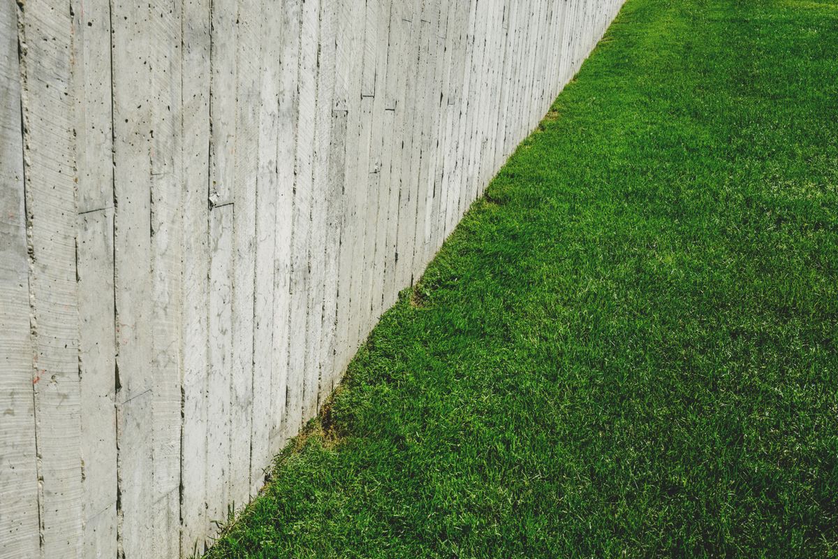 A minimalist outdoor scene featuring a wooden fence alongside a lush green lawn.