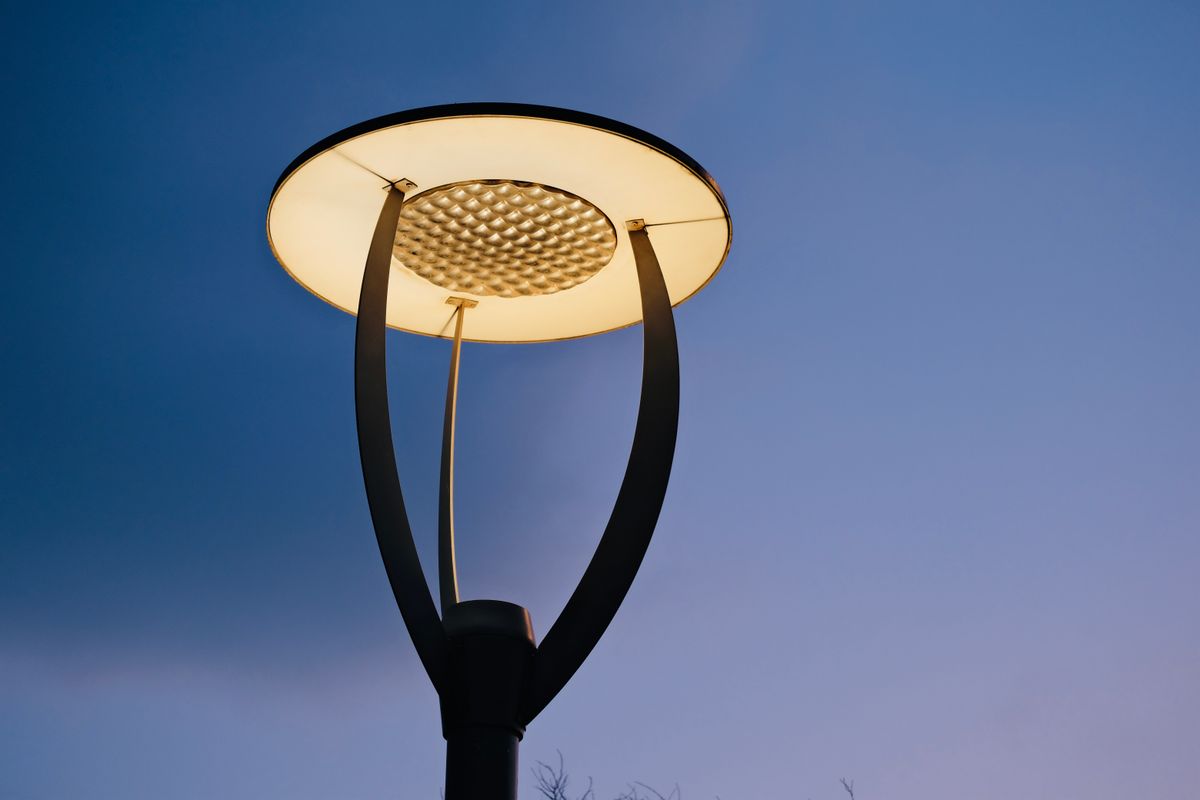 Close-up of a contemporary street lamp illuminating against a clear evening sky.