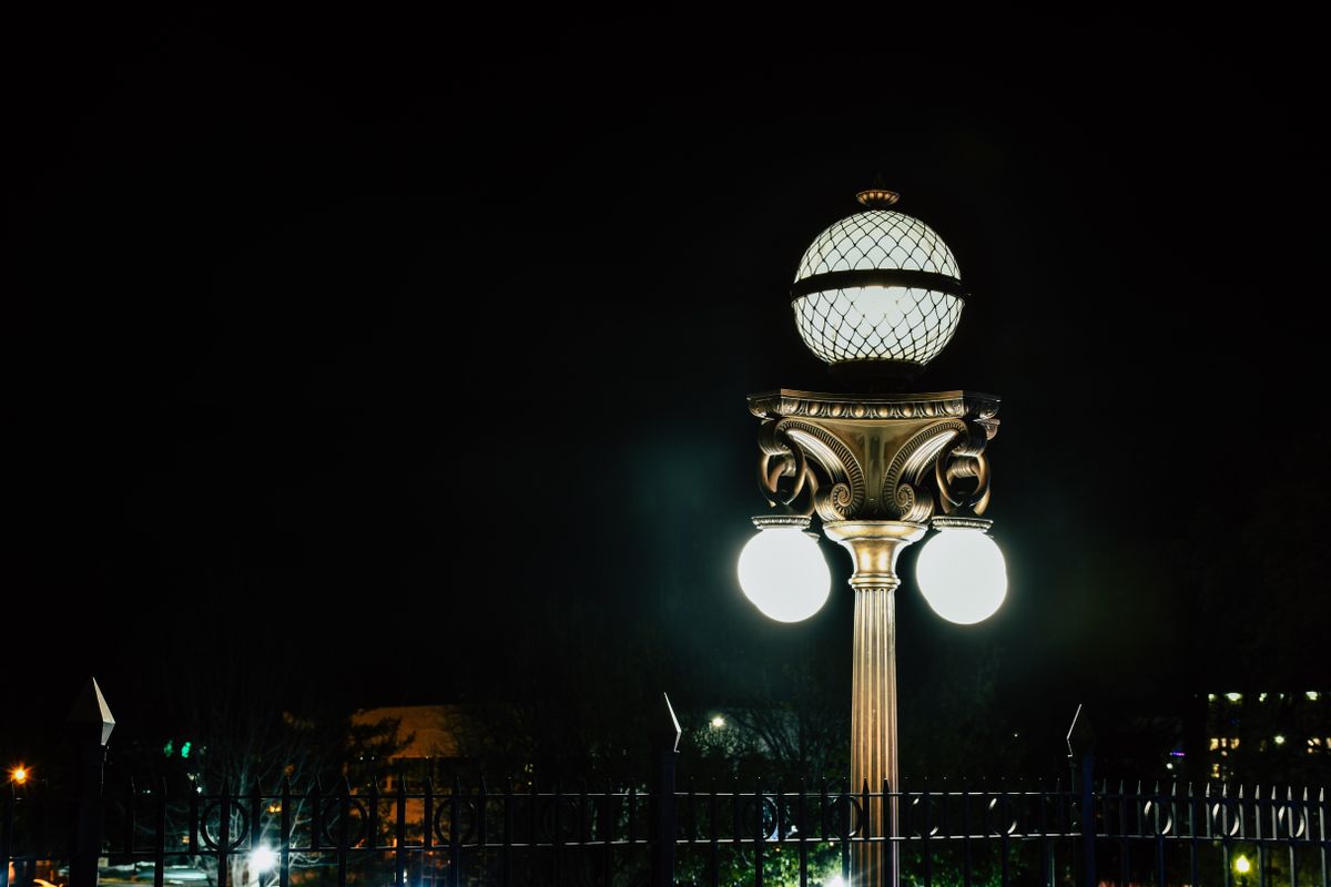 A beautifully lit ornate street lamp captured at night in an urban setting, highlighting details.