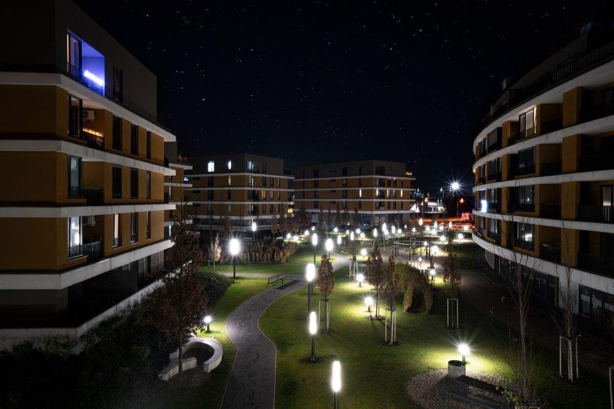Illuminated modern apartment complex in Bratislava captured under a starry night sky.