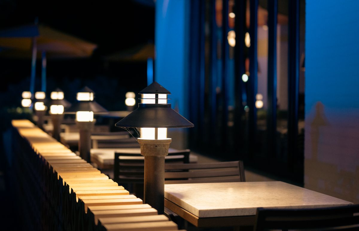 Atmospheric outdoor restaurant terrace illuminated by vintage lanterns, creating a cozy night ambiance.