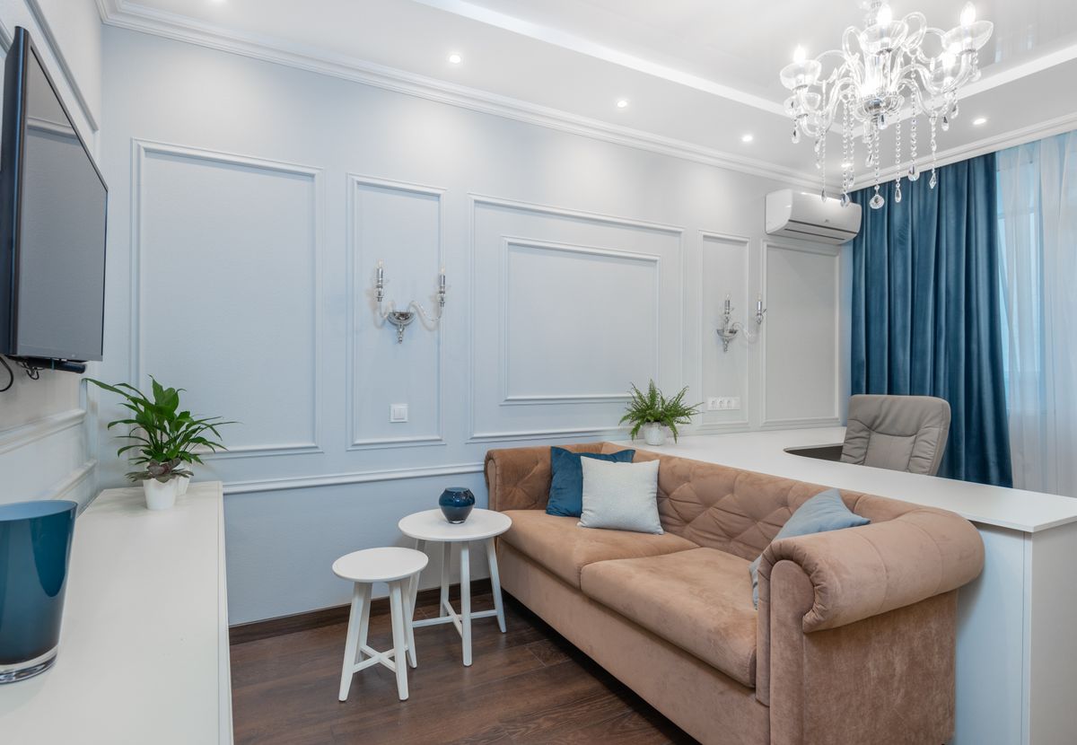 Bright and elegant living room featuring a chandelier, plush couch, and stylish decor.