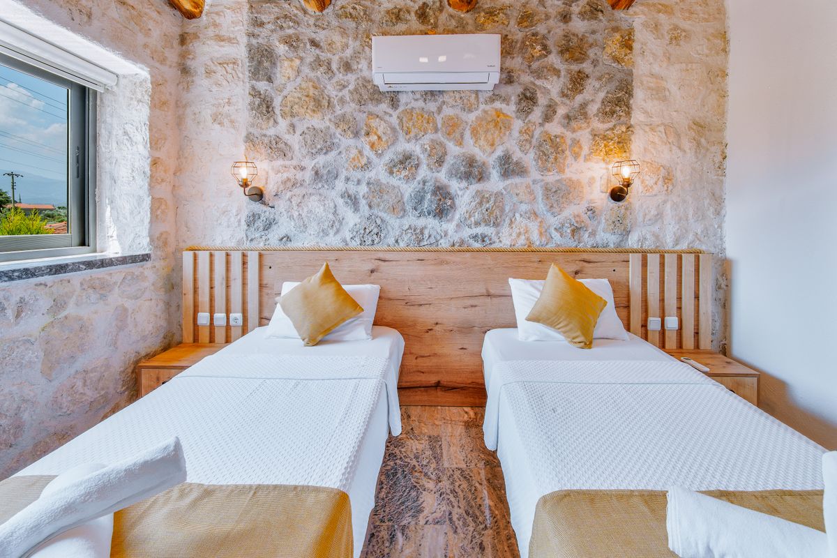 Rustic stone interior bedroom with twin beds, wooden accents, and natural light.