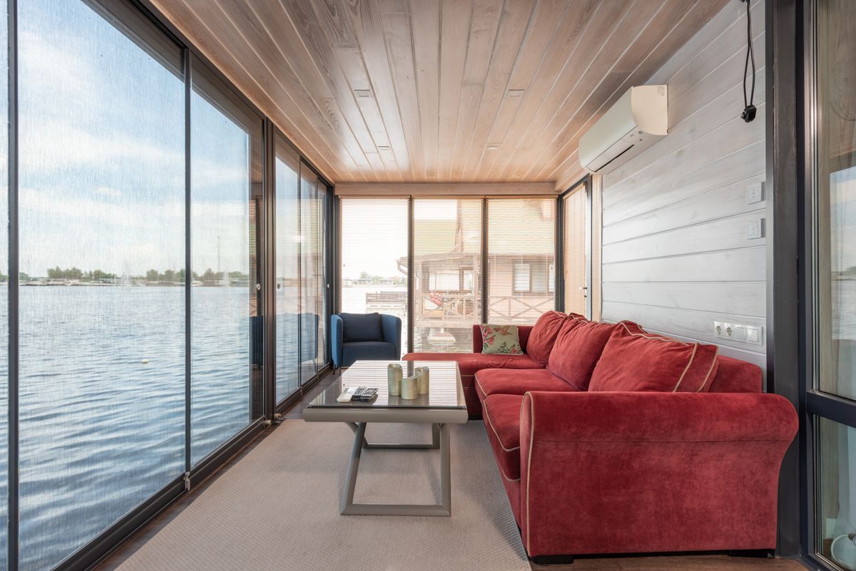 Stylish living room with red sofa and lake view through large glass doors.