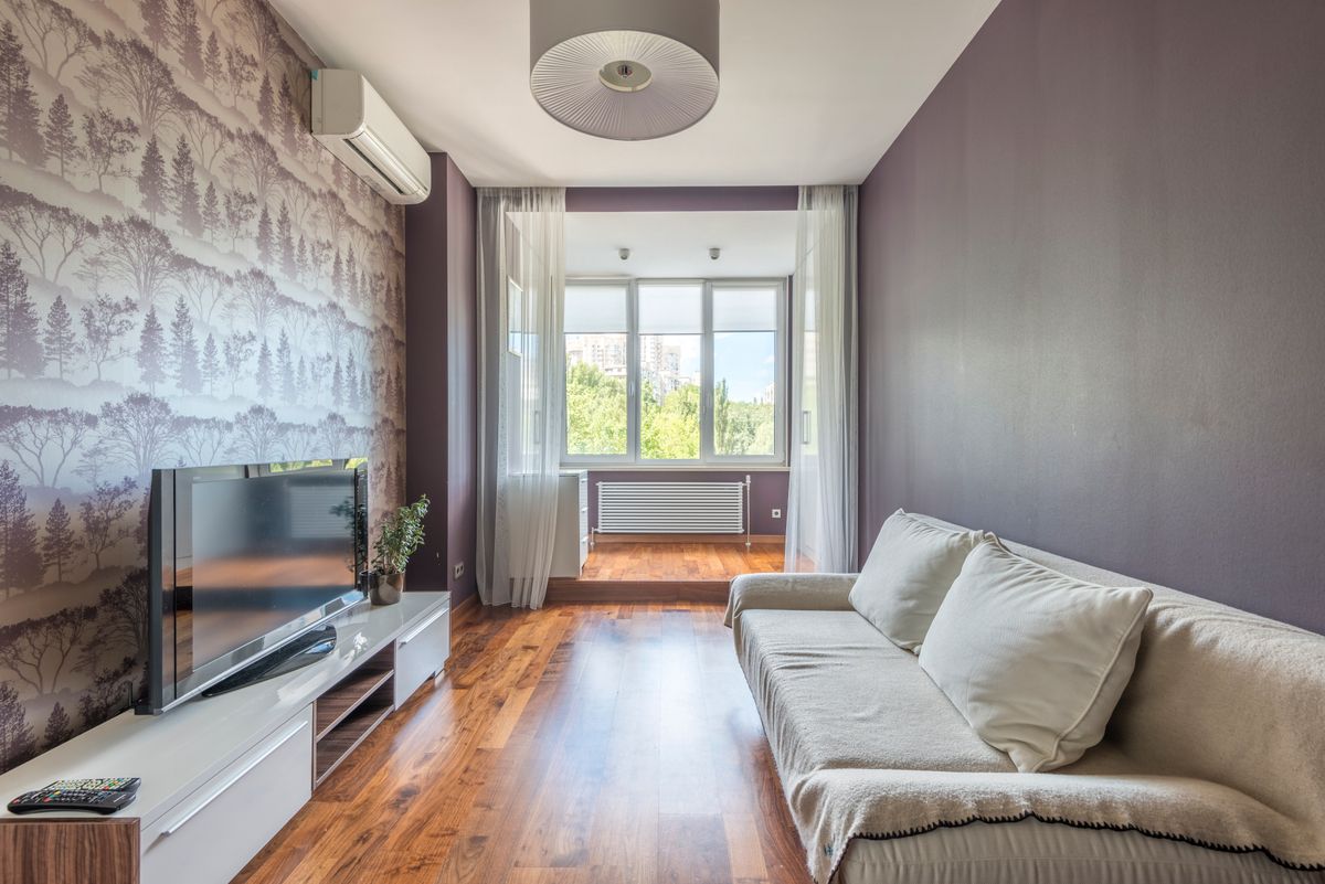 Spacious modern living room featuring air conditioning, a sofa, and large windows with natural light.
