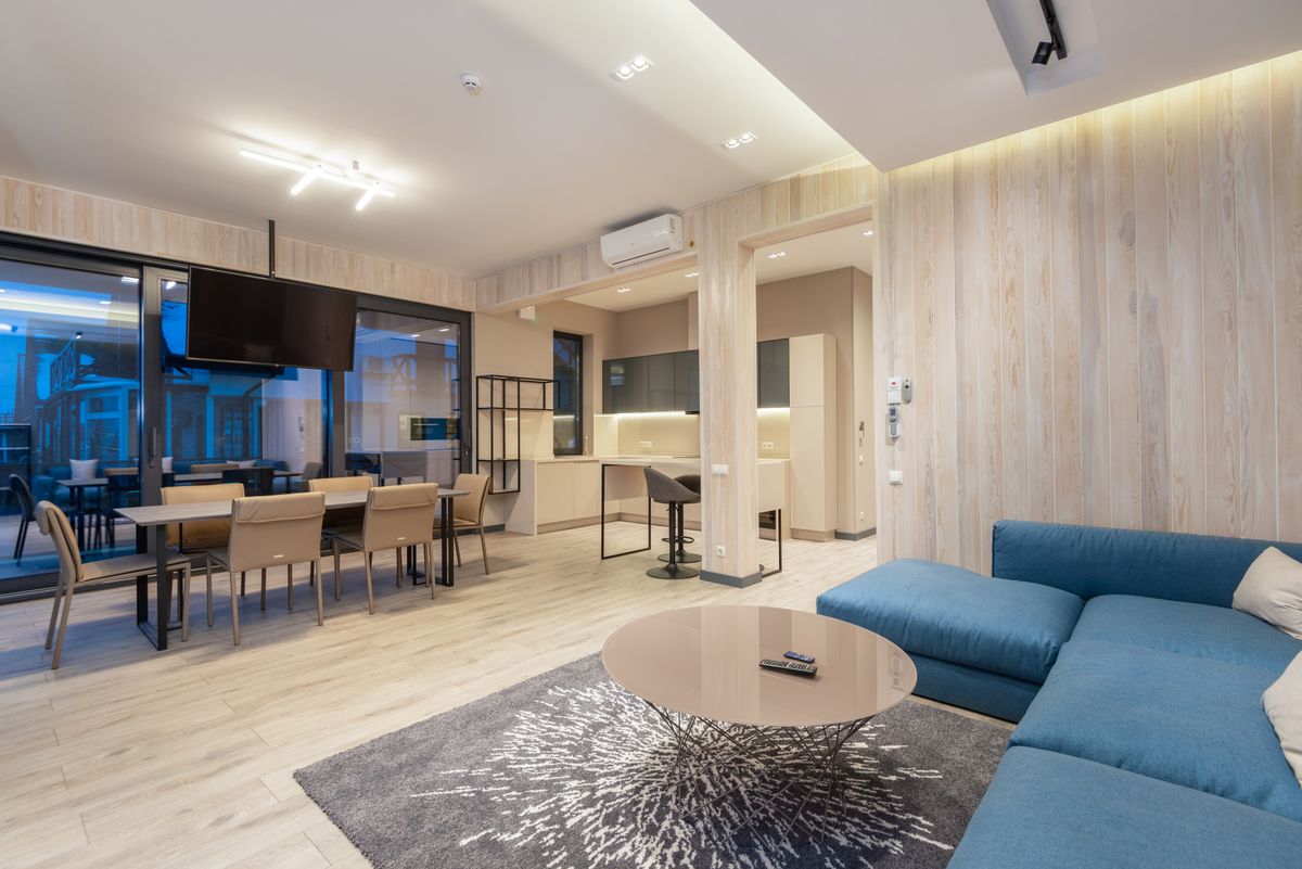 Comfortable corner sofa with round coffee table in spacious living room with dining and kitchen zones in spacious house