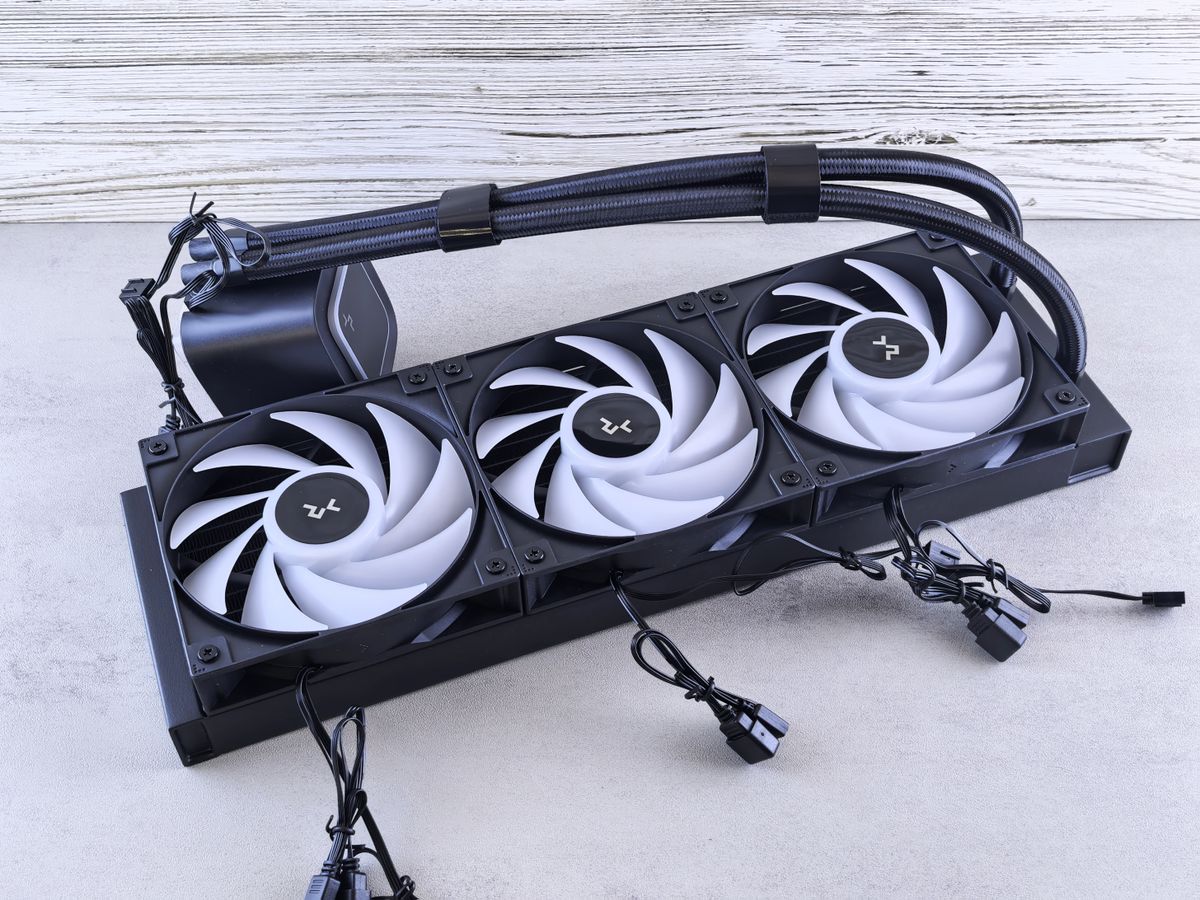 A modern triple fan CPU cooler with cables laid out on a concrete surface for cooling components.