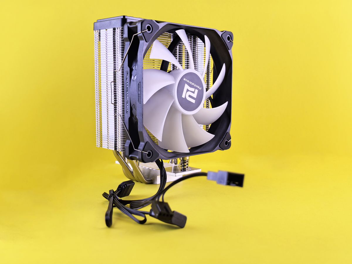 PC cooling fan with heatsink and cable against a bright yellow backdrop.