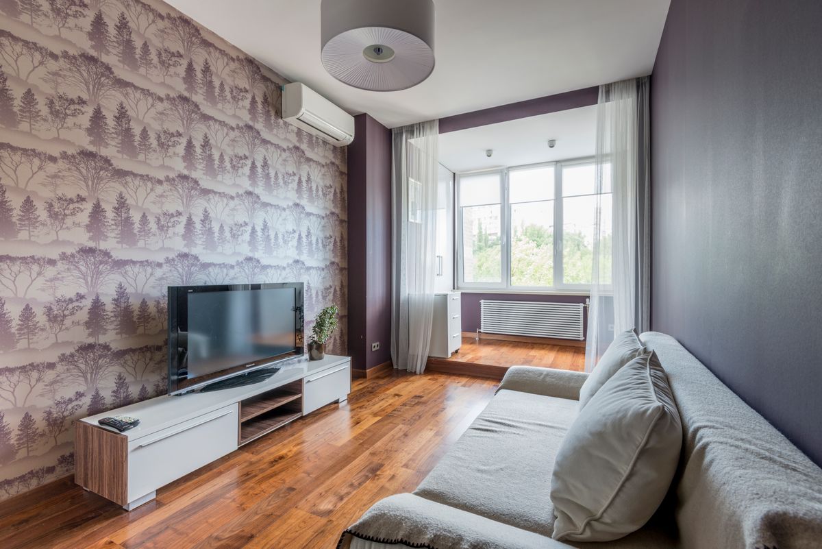 Contemporary living room featuring a TV, sofa, and decorative wallpaper accent wall.