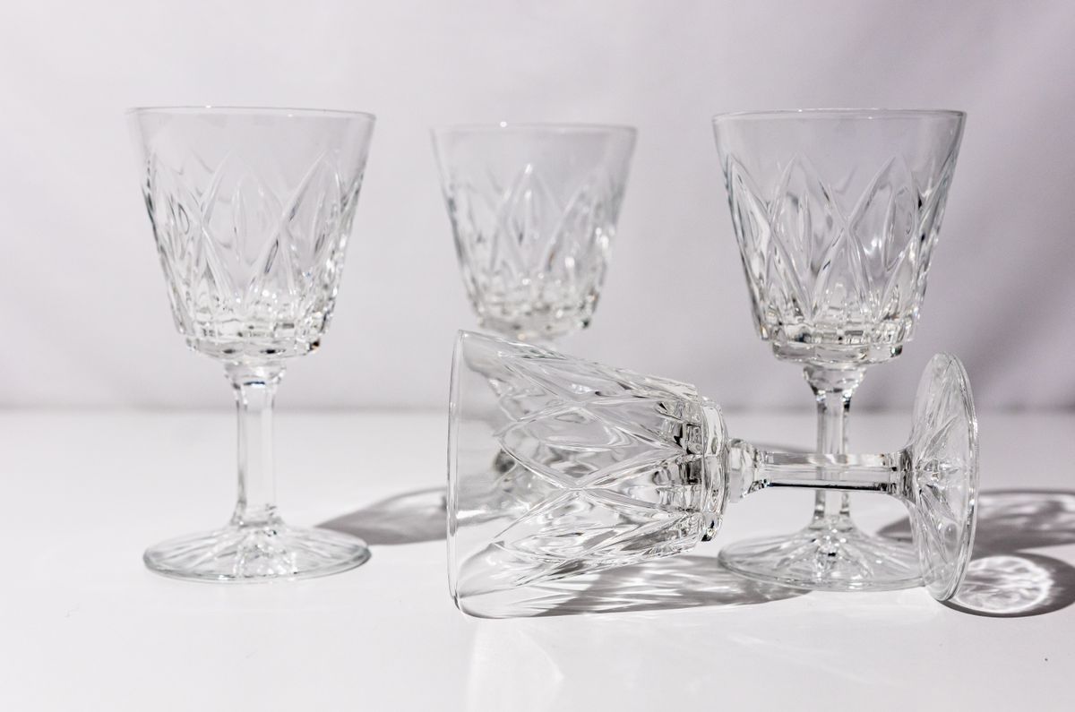 A set of elegant crystal wine glasses arranged on a white surface, showcasing intricate designs.
