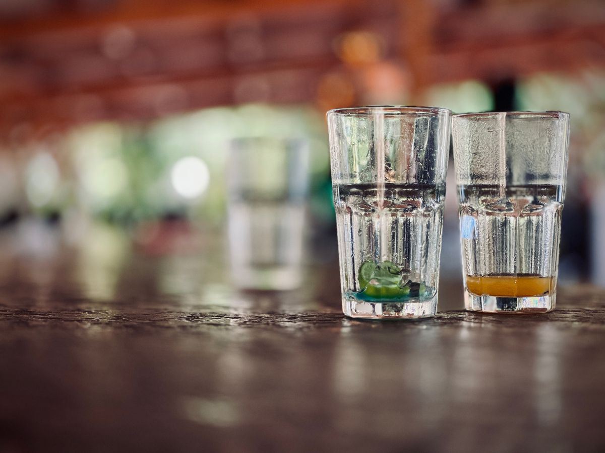 Two glasses with different liquid remnants on a wooden table indoors.