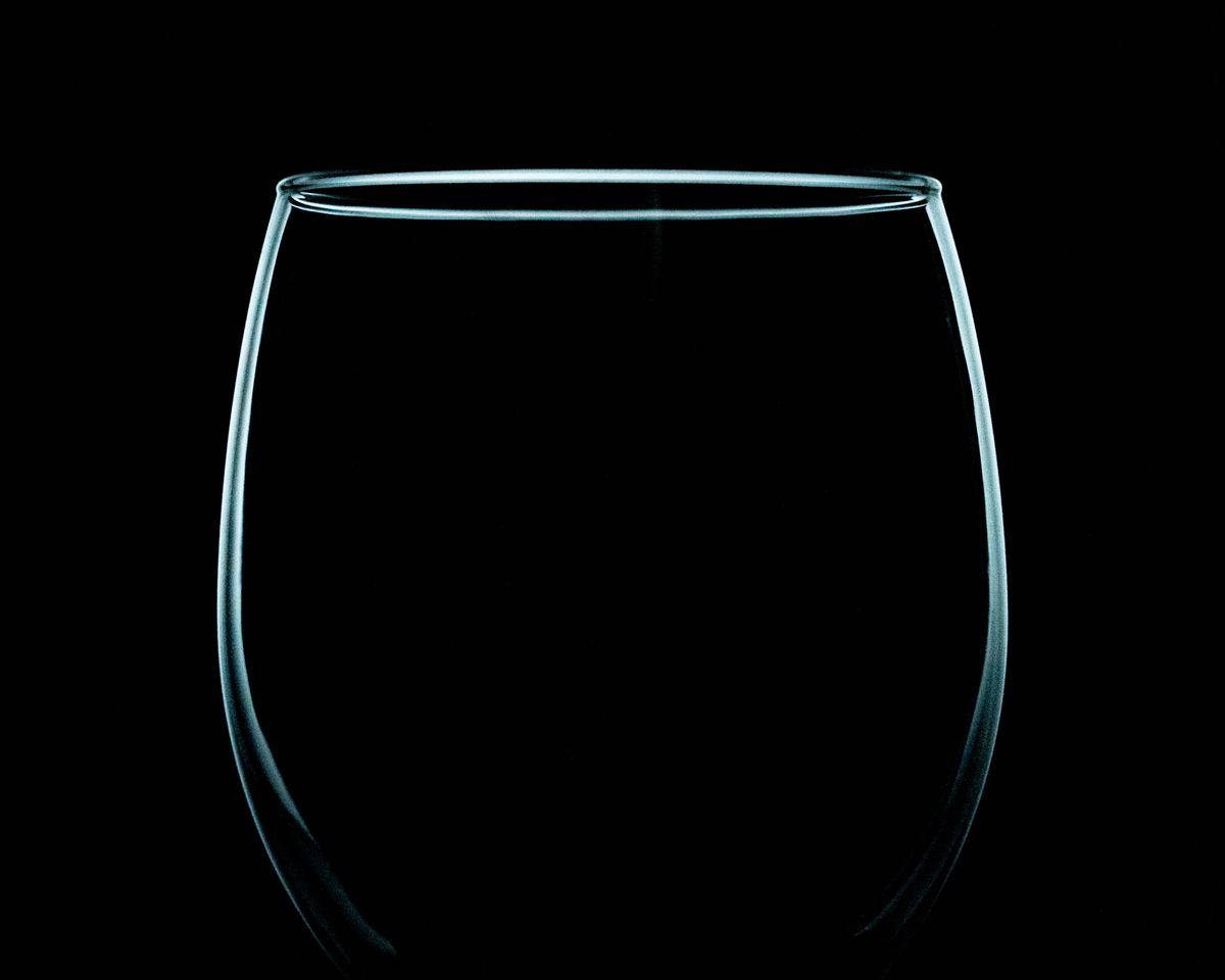 Elegant close-up of a clear wine glass on a black background, highlighting its simplicity.