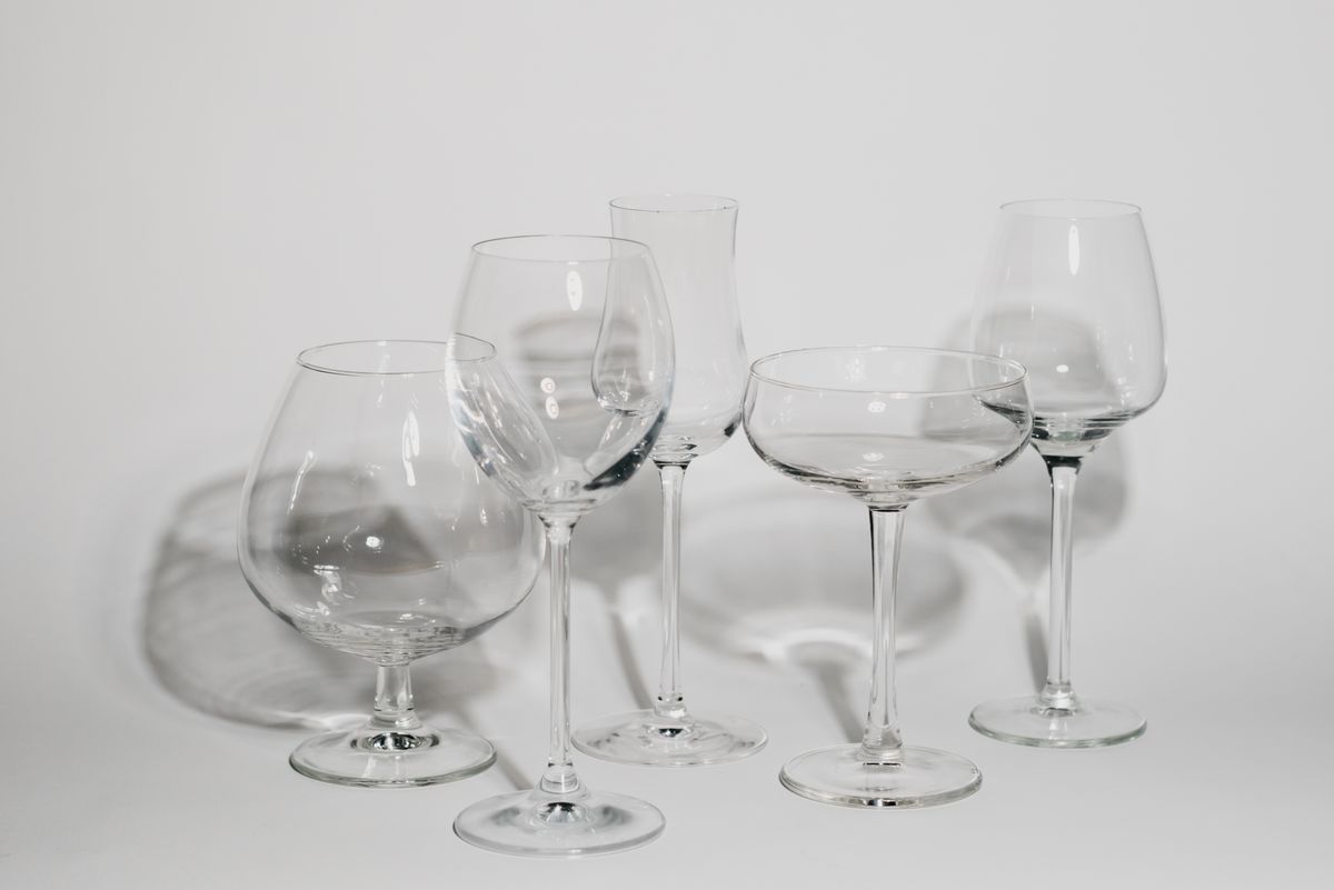 A collection of empty wine glasses casting shadows on a white surface, showcasing elegant glassware design.