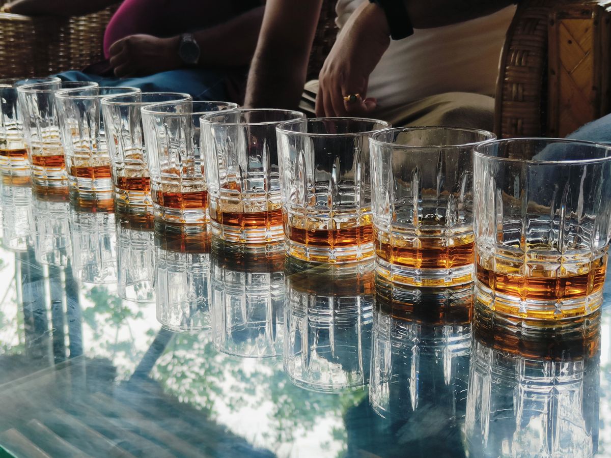 Elegant display of whiskey glasses reflecting on a glass table indoors.