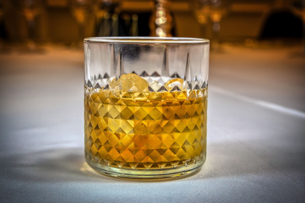 Detailed shot of whiskey in a textured glass on a table with soft lighting.