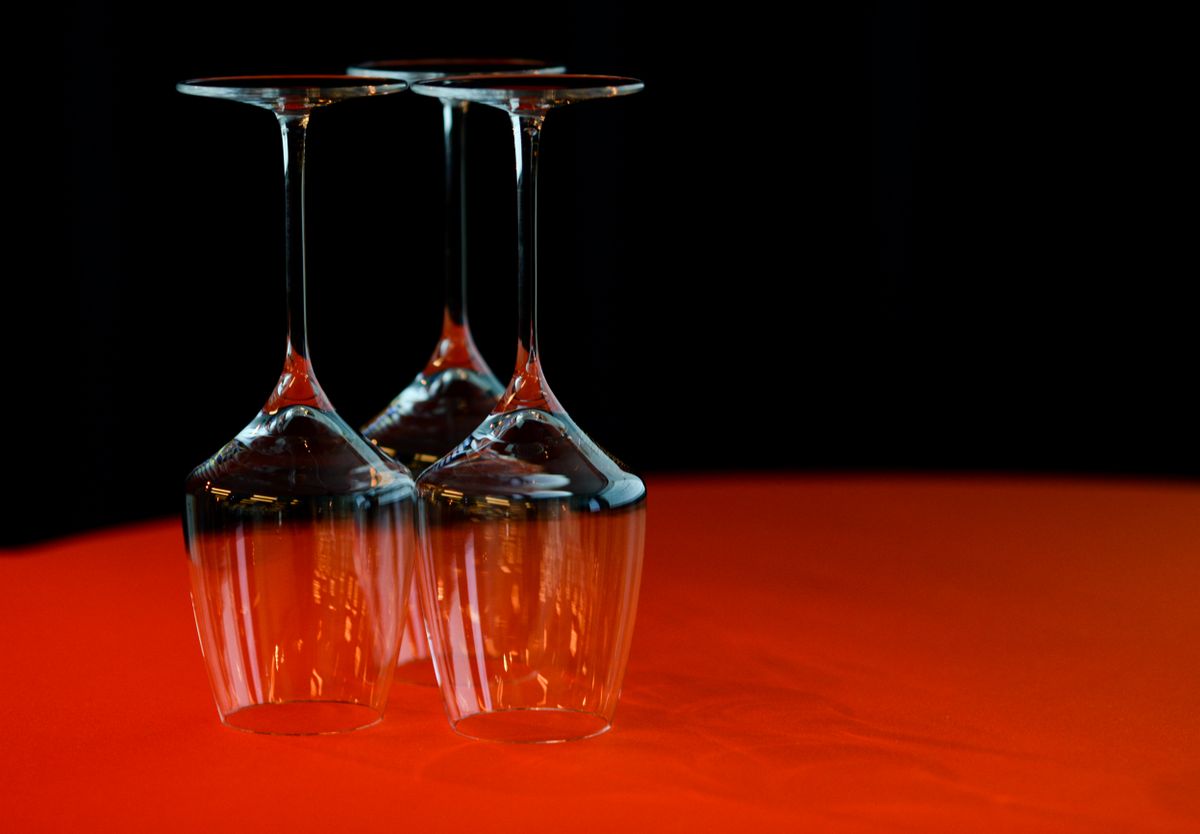 Elegant arrangement of upside-down wine glasses on a vibrant red surface with a dark backdrop.