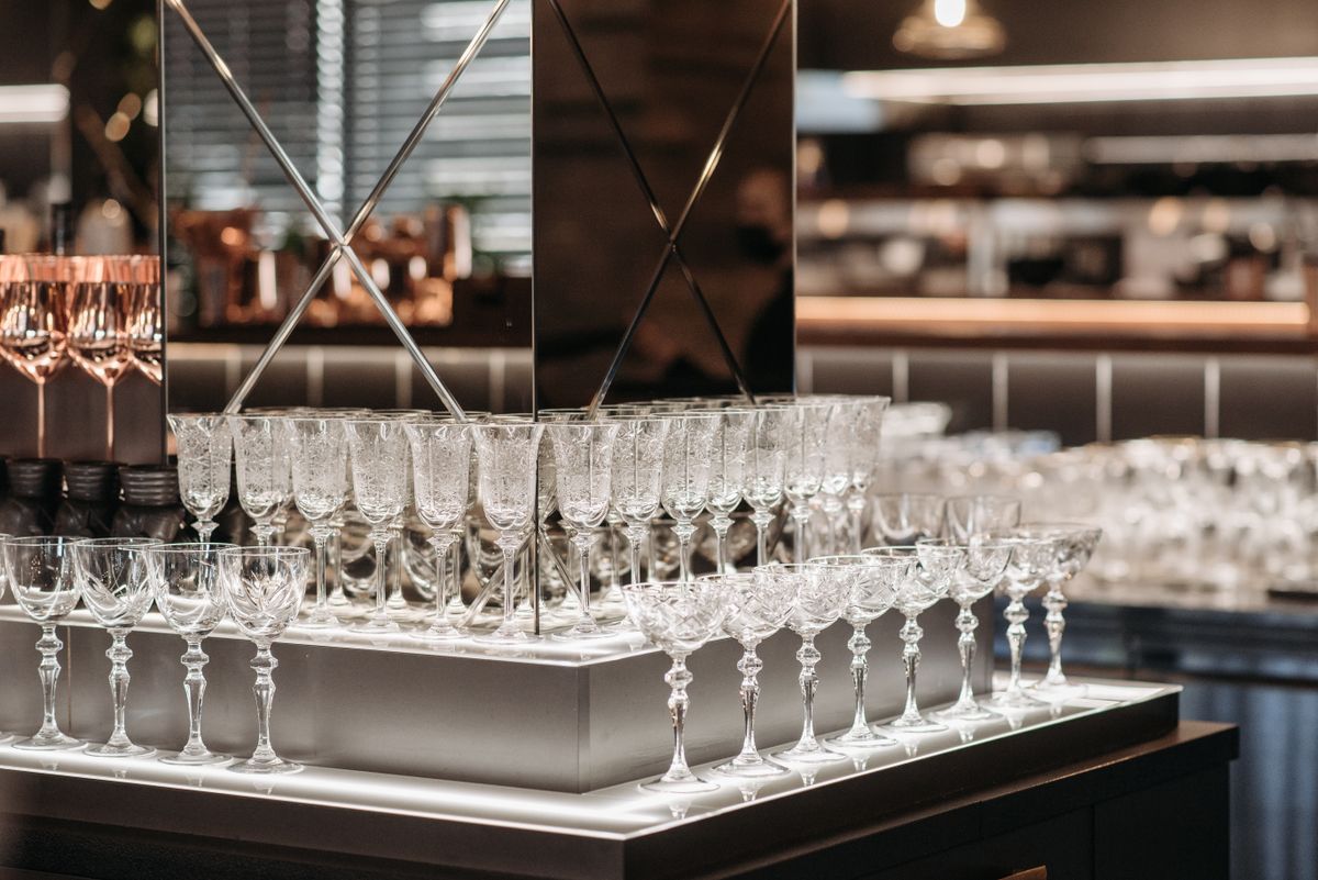 Elegant arrangement of wine glasses in a modern bar interior with reflective accents and warm lighting.